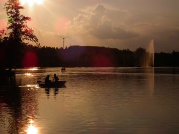 Silhouette people on lake against sky during sunset