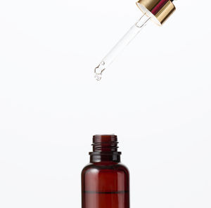Essential oil falling from the amber glass dropper. blue bottle of cosmetic oil with a 