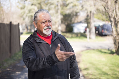 Senior man gesturing while standing at park