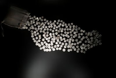 Low angle view of hand holding illuminated lighting equipment against black background