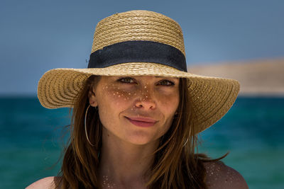 Portrait of woman wearing hat against sea