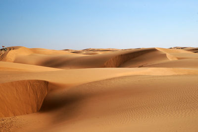 Sand dunes in desert against clear sky