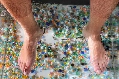 Low section of man having fish pedicure in water