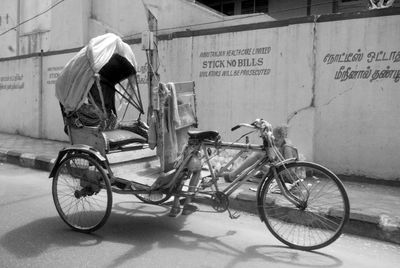 Tricycle parked on street against building during sunny day