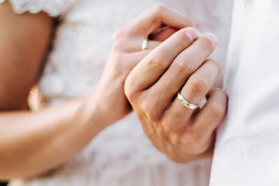 Midsection of couple holding hands during wedding ceremony