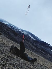 Man paragliding on mountain against sky during winter