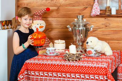 Portrait of smiling girl sitting on table at home