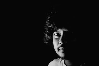 Close-up portrait of young man against black background