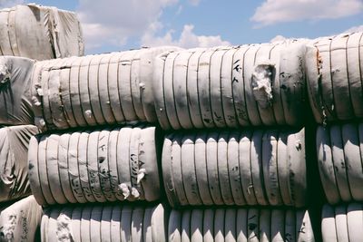 Stack of cotton on field against cloudy sky