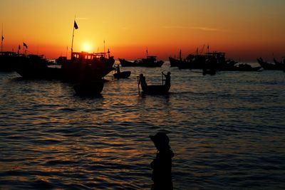 Silhouette man on boat in sea against sky during sunset