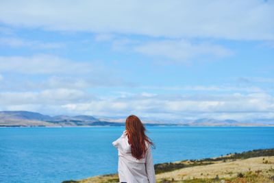 Rear view of woman looking at lake against sky