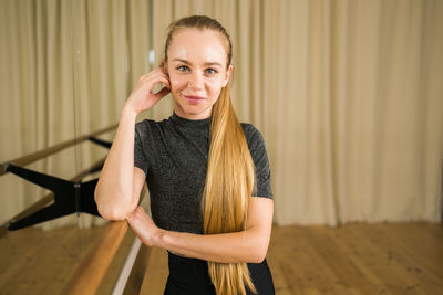 Portrait of young woman standing against curtain