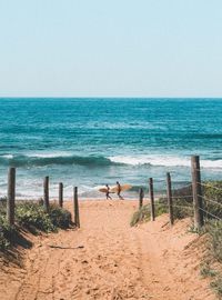 Side view of friends with surfboards walking at beach