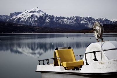 Boat moored on lake by mountains