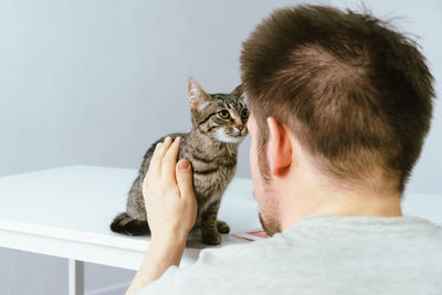 Man plays with a kitten. hugs him and kisses him