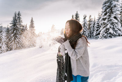 Young woman standing on snow covered field