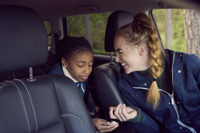 Smiling woman sitting with daughter in car