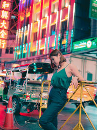 Full length of woman standing on illuminated city at night