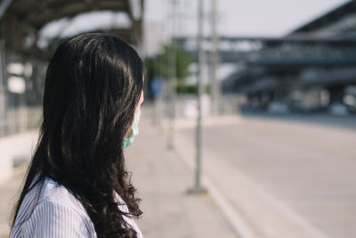 Side view of woman wearing mask standing on street