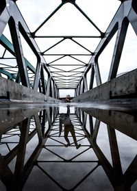 Digital composite image of man reflection in puddle on bridge