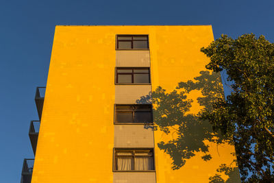 Low angle view of yellow building on sunny day