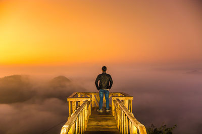 Man standing at observation point against sky during sunset