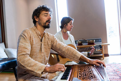 Musicians playing harmonium and sitar at home