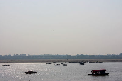 Boats sailing in sea against clear sky