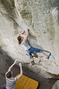 Young woman bouldering in the forest of fontainebleau close to paris