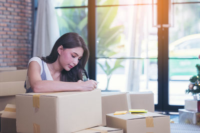 Portrait of woman sitting in box at home