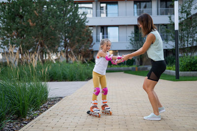 Mother helps daughter learn to roller skate