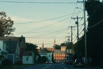 Cars on road by buildings against sky in city