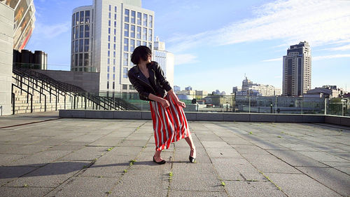 Woman with umbrella against sky in city