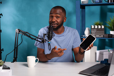 Young man using mobile phone while sitting on table