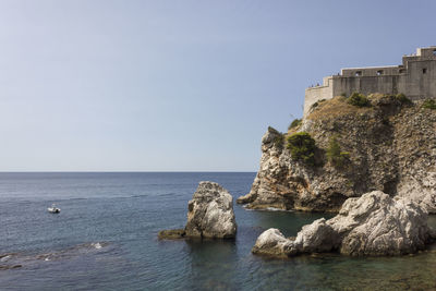 Rocks in sea against clear sky