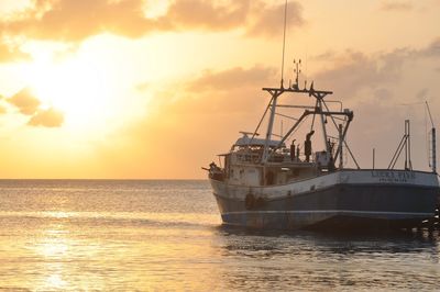 Boats in sea at sunset