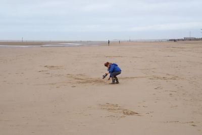 Full length of boy on beach against sky