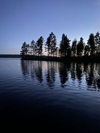 Silhouette trees by lake against sky