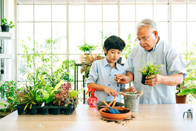 Grandfather assisting grandson in greenhouse