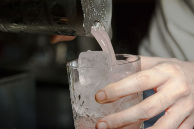 Cropped hand pouring drink in glass