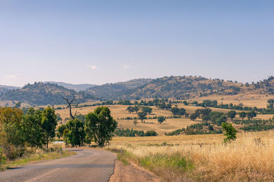 Road amidst field against sky