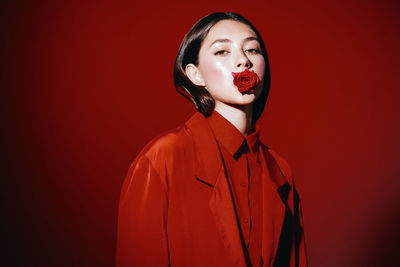 Portrait of young woman wearing mask against wall