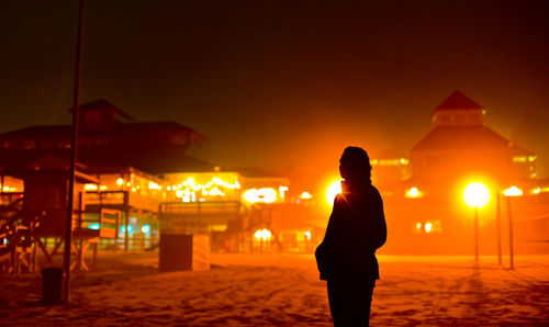 Silhouette woman standing at beach during sunset