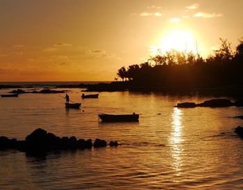 Silhouette of boats in lake during sunset