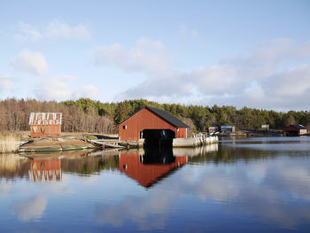 Built structure by lake and building against sky