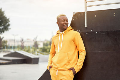 Smiling young man looking away against sky