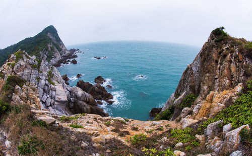 Scenic view of cliff by sea against sky