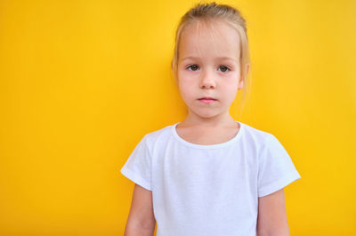 Portrait of young woman against yellow background