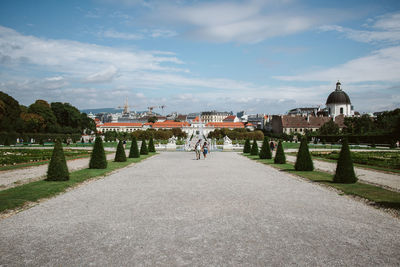 People walking in city against cloudy sky