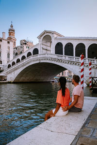 People on bridge over canal against sky